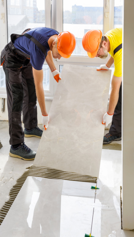 Pracownicy firmy remontowej Multitechnik układający płytki podłogowe w kuchni u klienta z Sopotu.