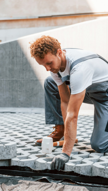 Brukarz z firmy remontowej układający kostkę brukową na posiadłości w Gdańsku.